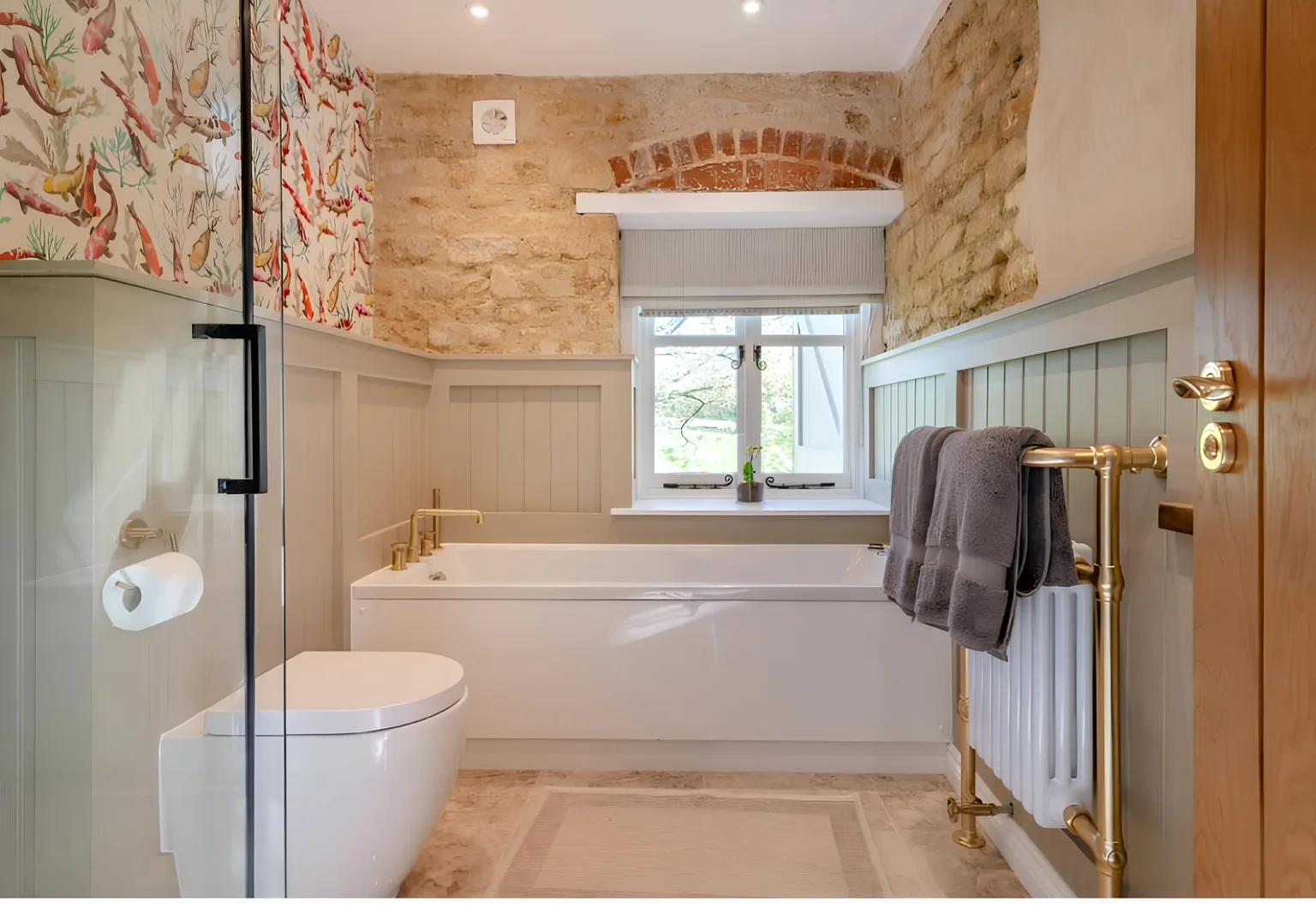 Modern bathroom renovation with exposed stone wall and freestanding bath by N. Patten Building & Carpentry, Somerset.