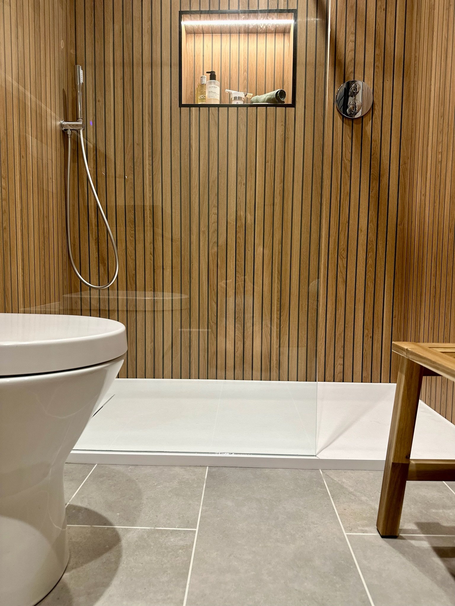 Contemporary walk-in shower with wood-panelled feature wall, part of bespoke bathroom design in Dorset.