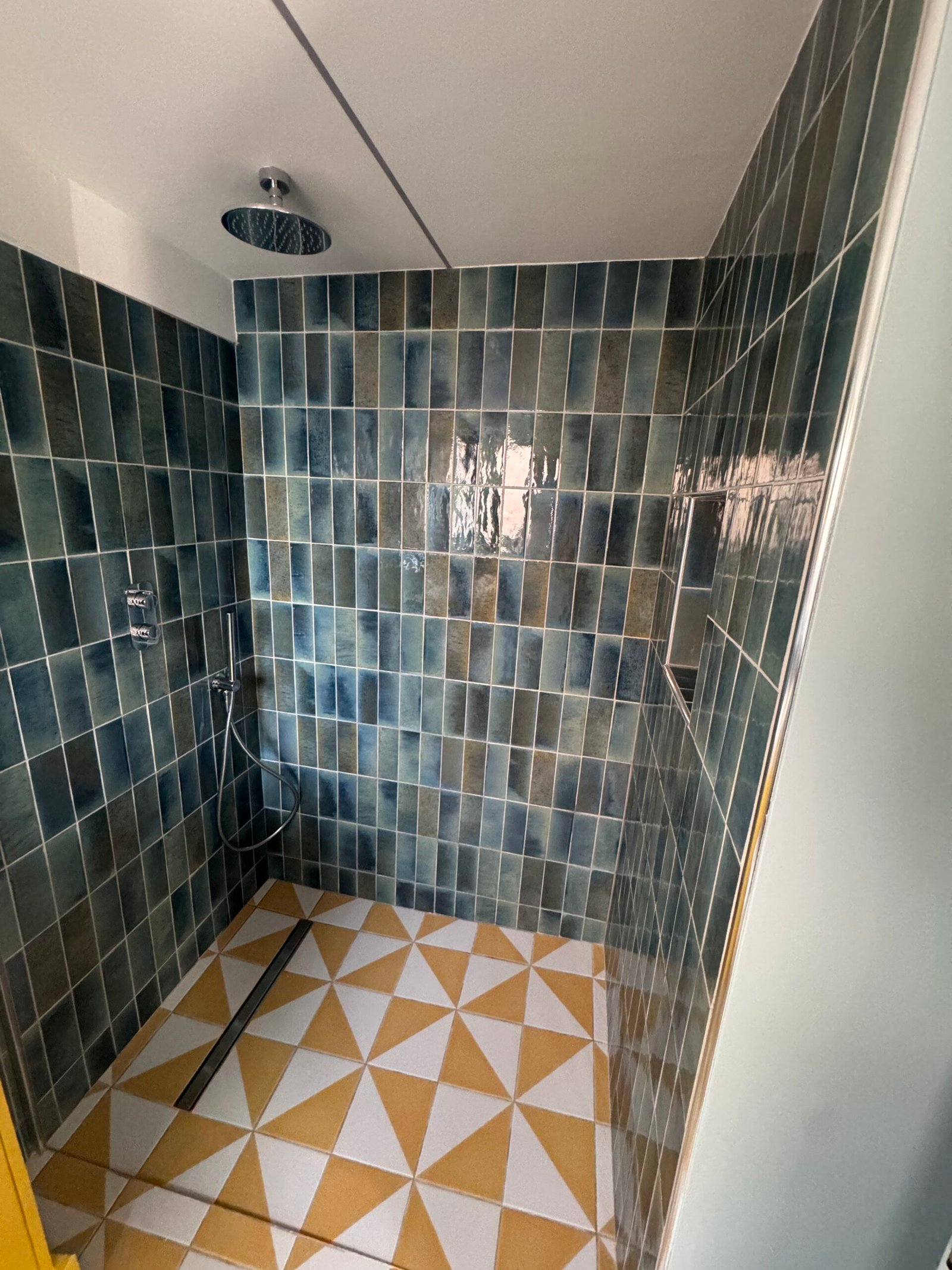 Decorative blue tiled shower area in the renovated bathroom