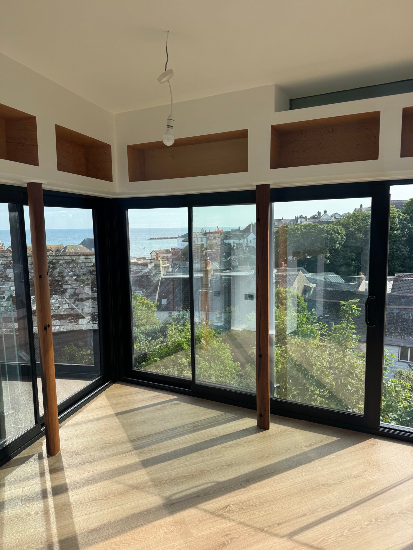 Light-filled room with large black-framed glazing and timber-effect floor