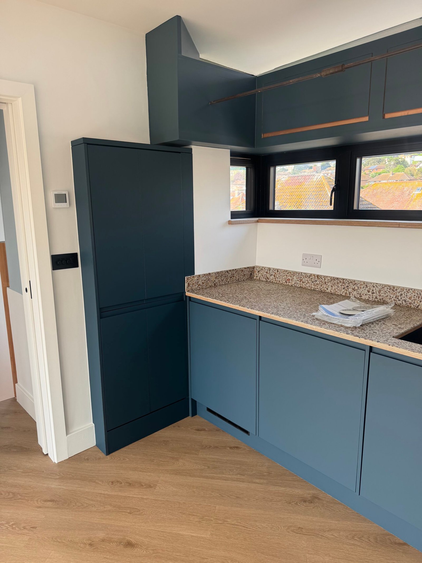 Modern blue fitted kitchen with worktop and window at Rusty Towers