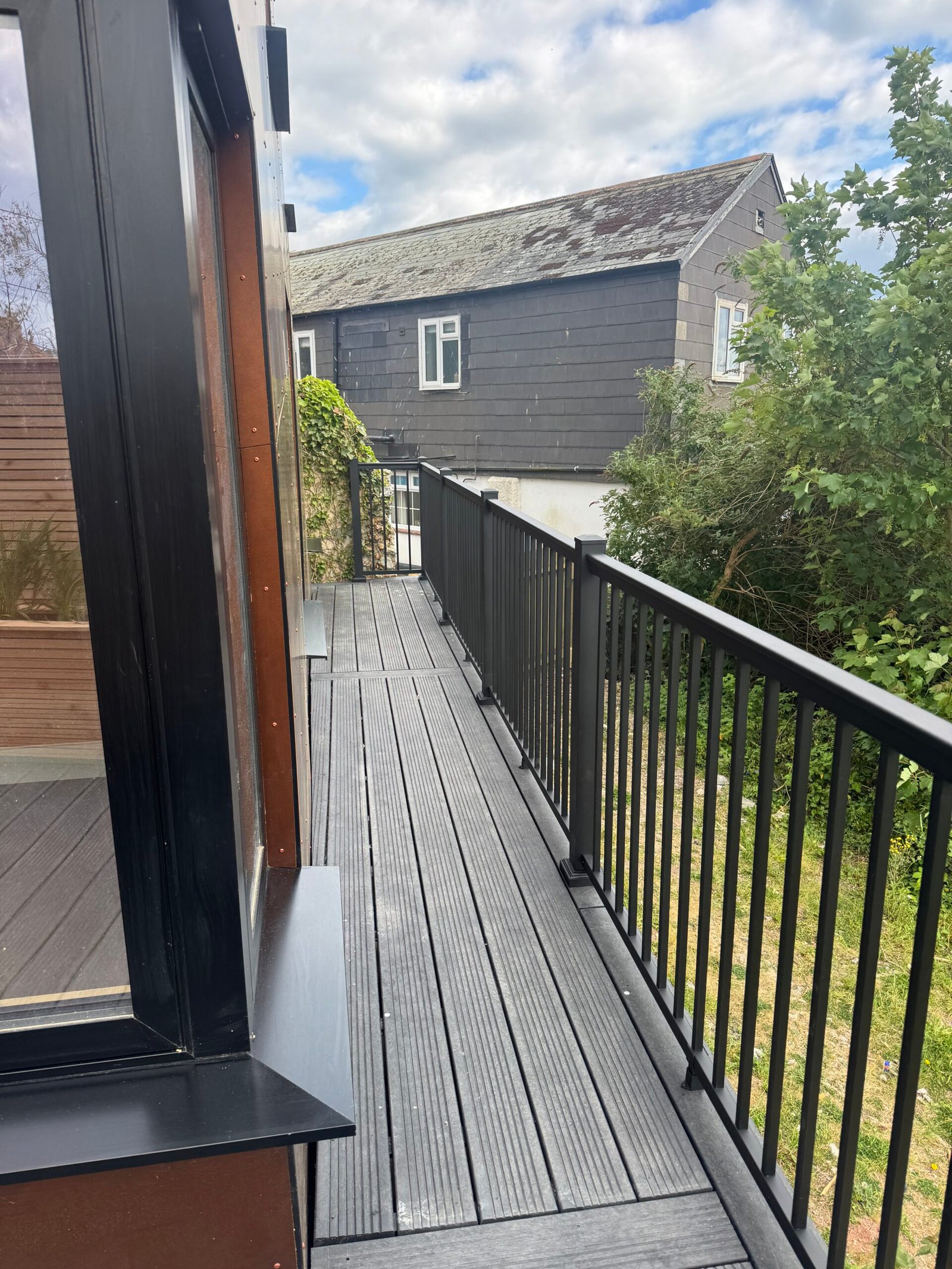 Exterior decked walkway and black metal railing alongside Rusty Towers