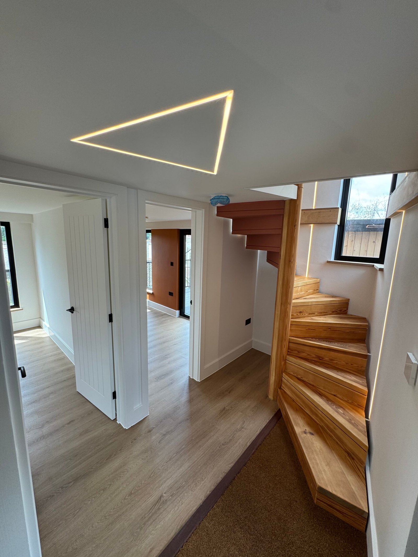 Timber staircase and contemporary ceiling lighting inside Rusty Towers