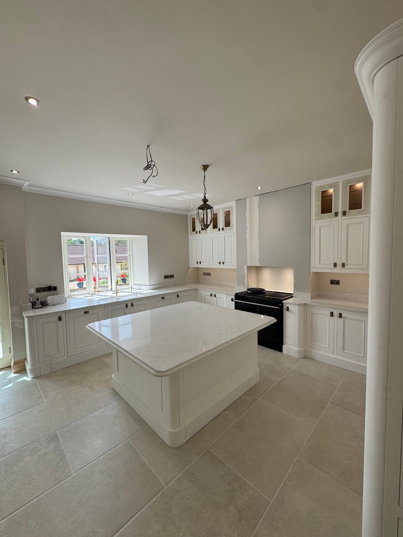 Kitchen after renovation with white cabinetry, central island and new stone-effect flooring