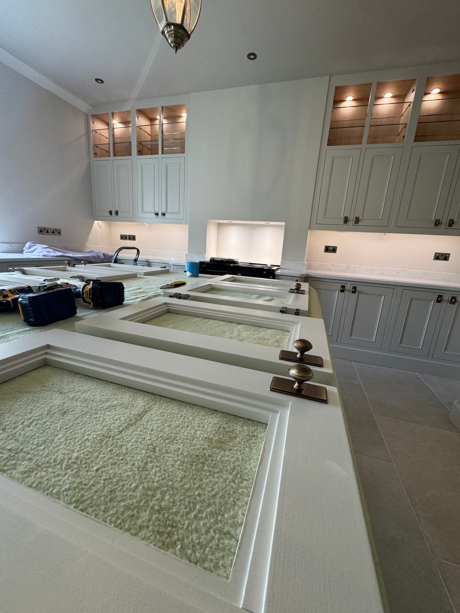 Kitchen installation in progress with cabinet doors and fittings laid out for assembly